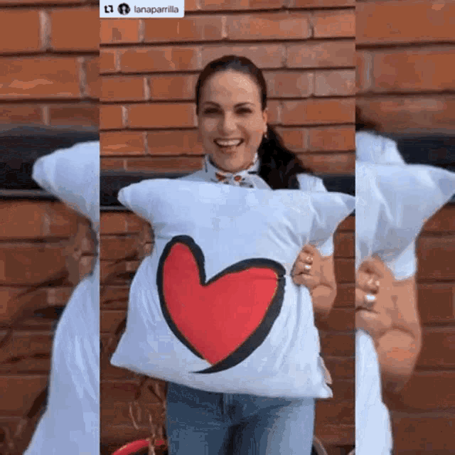 a woman holding a pillow with a red heart on it