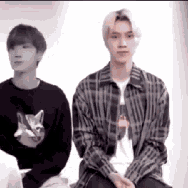 a man in a plaid shirt is sitting next to a man in a black sweater .