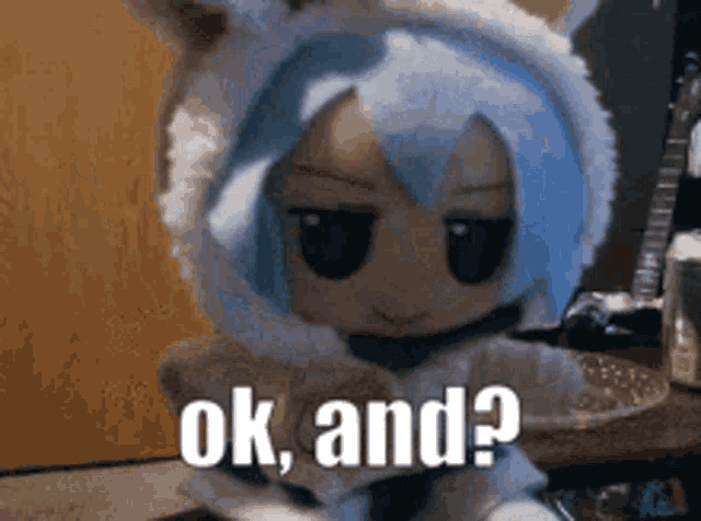 a stuffed animal with blue hair is sitting on a table with the words ok and ? on it .