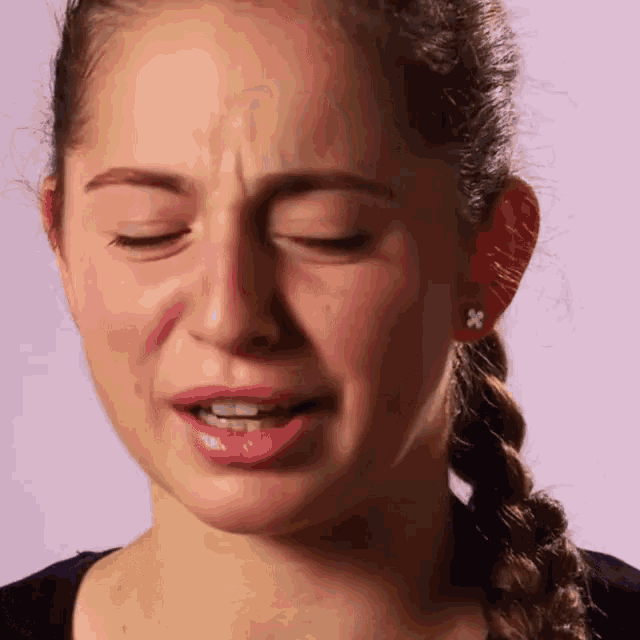 a close up of a woman 's face with her eyes closed and a braided hair