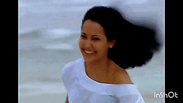 a woman in a white shirt is smiling on the beach