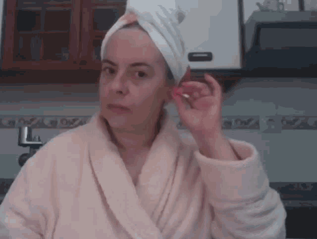 a woman with a towel wrapped around her head looks at the camera