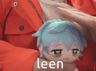 a person in a red jacket is holding a stuffed animal that says leen on it .