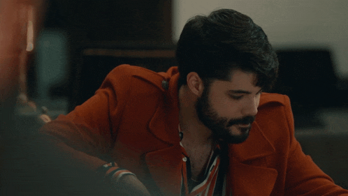 a man with a beard is wearing a red coat