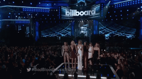 a group of women singing on a stage in front of a billboard