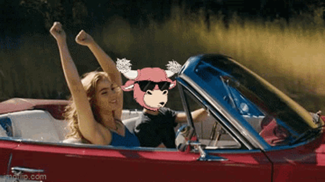 a woman and a child are riding in a red convertible with their arms in the air ..