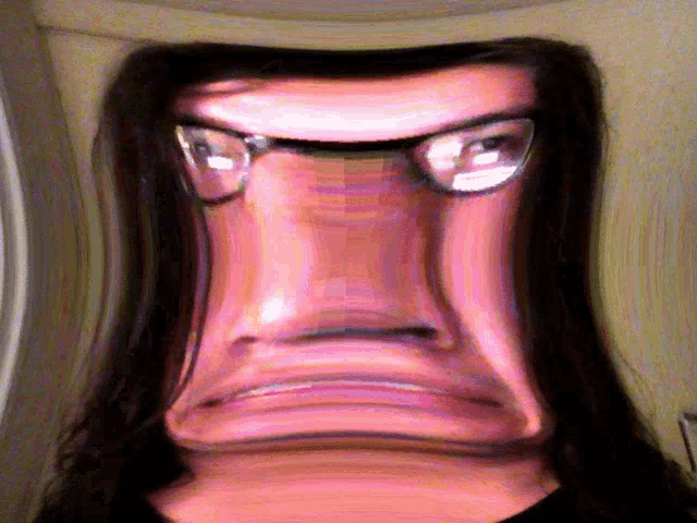 a close up of a person 's face with long hair and glasses