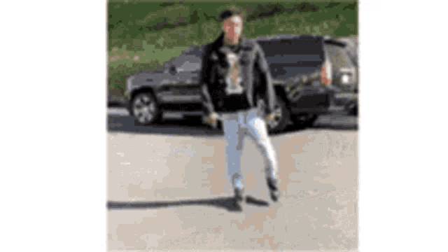 a man in a black jacket and white jeans is standing in front of a black suv