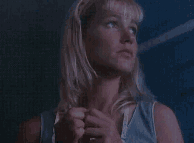a close up of a woman 's face in a blue tank top .