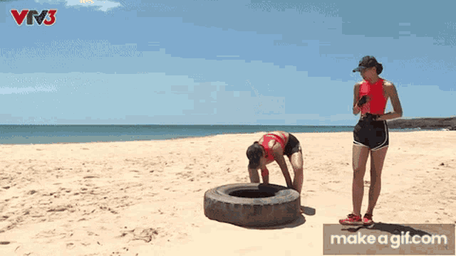 a woman is crawling into a tire on the beach with a make a gif.com link below her