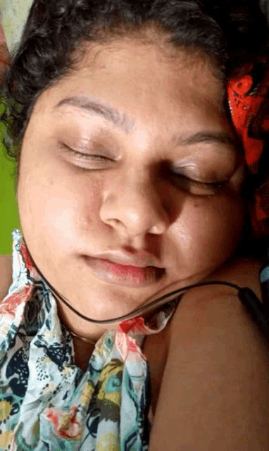 a close up of a woman sleeping with her eyes closed and a cord around her neck