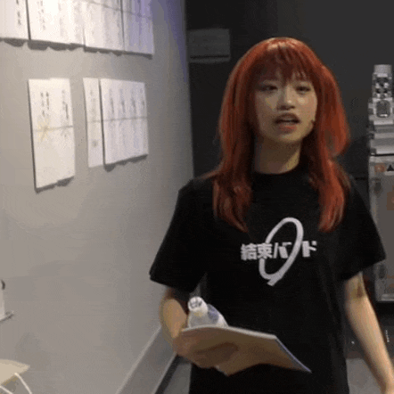 a woman with red hair is wearing a black t-shirt and holding a clipboard .