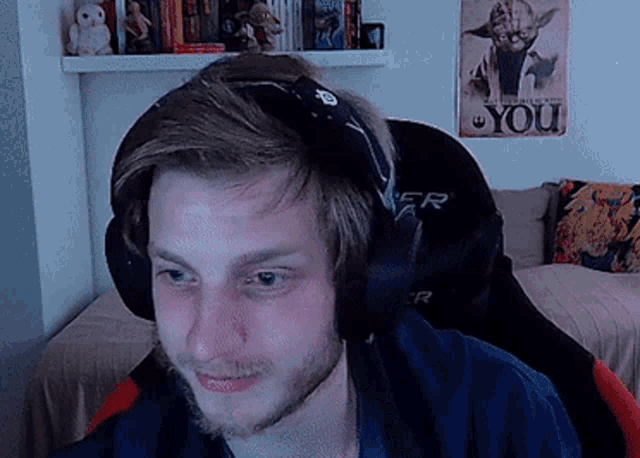 a man wearing headphones looks at the camera in front of a poster that says you