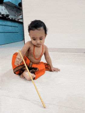 a baby is sitting on the floor and holding a stick