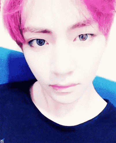 a young man with pink hair and blue eyes is wearing a black shirt