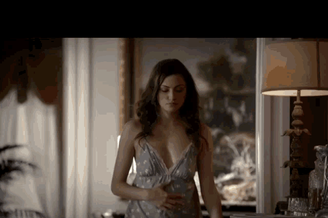 a woman standing in front of a lamp and a mirror