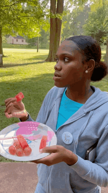 a woman holding a plate of watermelon slices with a badge that says ' i love you ' on it