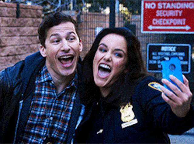 a man and a woman are taking a selfie in front of a sign that says no standing security checkpoint