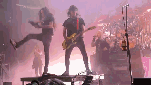 a man is playing a guitar on stage while another man stands on a stage
