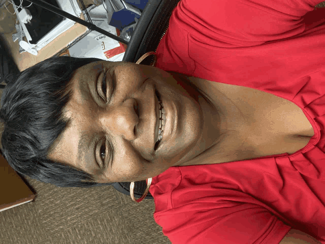 a woman in a red shirt is smiling and looking at the camera
