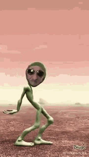 a green alien with sunglasses on is dancing in the desert .
