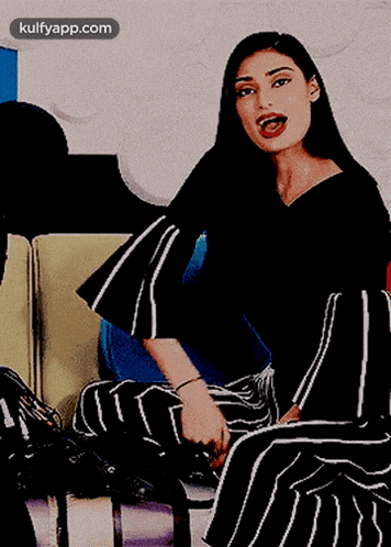 a woman in black and white striped pants is sitting on a couch and smiling for the camera