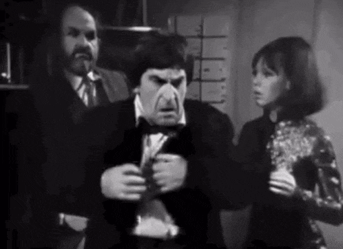 a group of people are standing next to each other in a room . one of the people is wearing a mask .