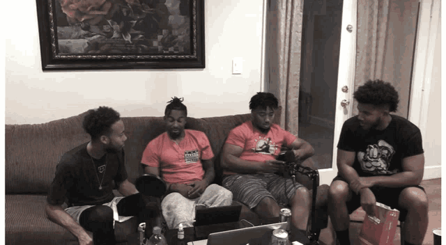 four men sitting on a couch with one wearing a shirt that says ' miami ' on it
