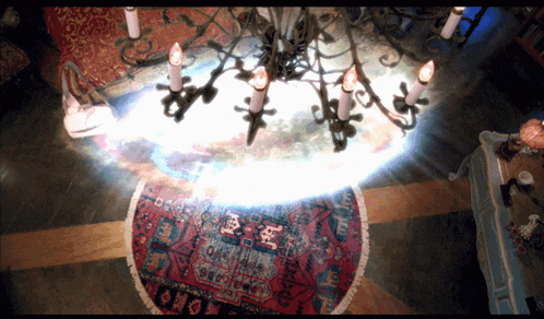 a chandelier with candles hanging from it is surrounded by a round rug