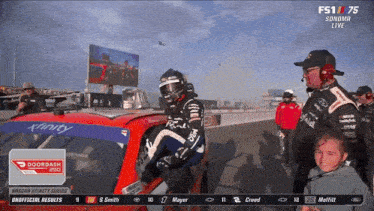 a man in a helmet is getting out of a race car at a nascar event