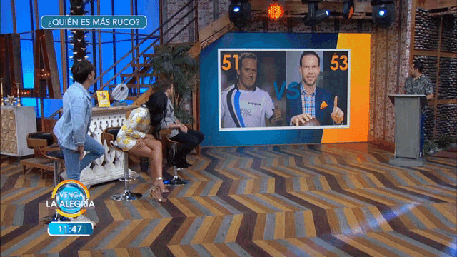 a woman sits on a chair in front of a screen with 51 vs 53 on it