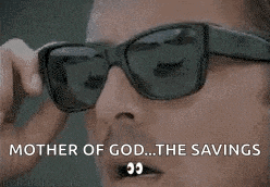 a man wearing sunglasses is holding a cell phone in his hand .