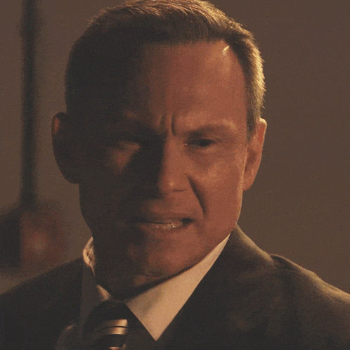 a man in a suit and tie is smiling with his eyes closed