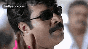 a man with a mustache and sunglasses is looking at something .