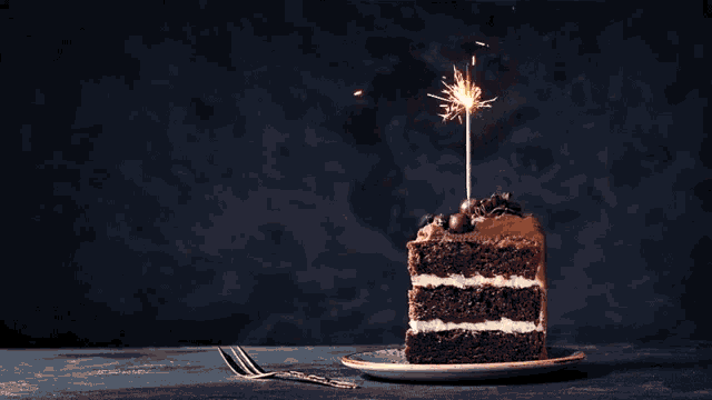 a slice of chocolate cake with a sparkler on it