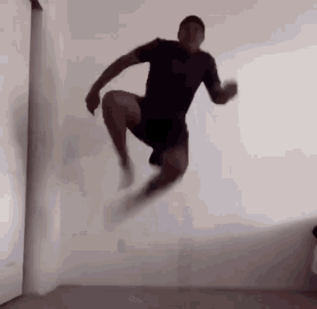a man is jumping in the air in front of a white wall .