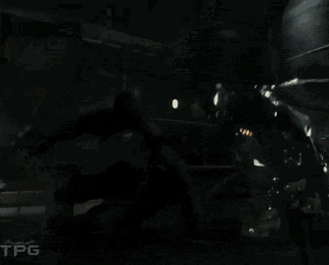 a close up of a robot with wings and glowing eyes in a dark room .