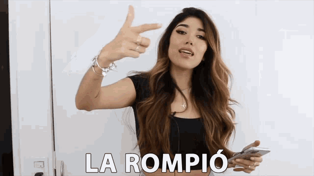 a woman holds a cell phone and says la rompio on the screen