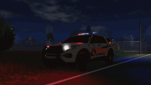 a sheriff 's car is parked on the side of a road at night