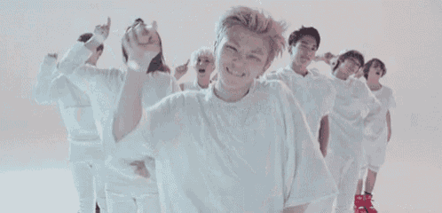 a group of people in white clothes are dancing in a room .