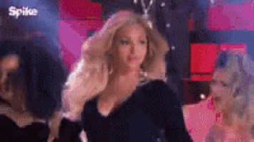 a barbie doll in a black dress is standing in front of a crowd .