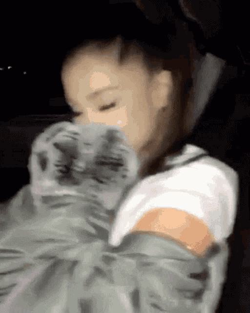 a blurry picture of ariana grande holding a cat in her lap .