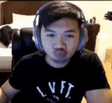 a man wearing headphones and a black shirt is making a funny face while sitting in a chair .