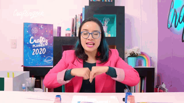 a woman sitting at a desk with a crafty planner on the wall behind her