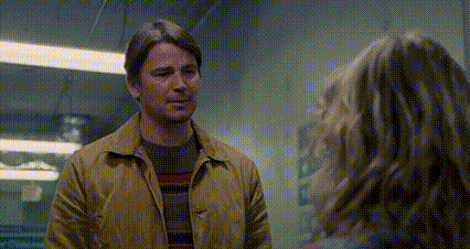 a man in a yellow jacket is standing next to a woman in a room .