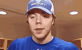 a man wearing a blue hat and a blue shirt is standing in a locker room .