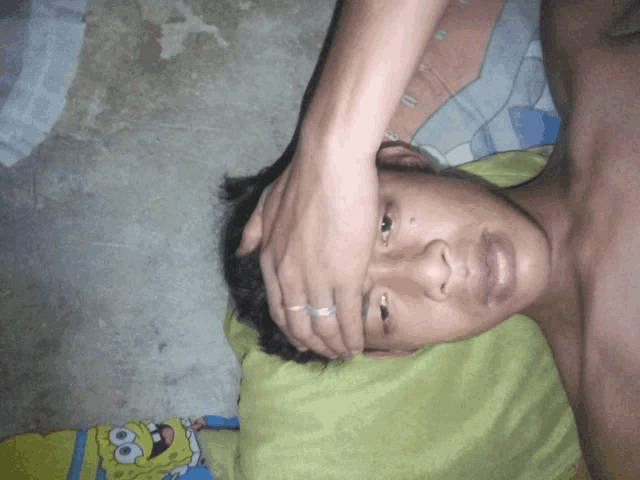a man laying on a bed with a spongebob pillow on it