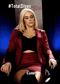 a woman in a red suit and skirt is sitting in a chair with her eyes closed and says `` cute '' .