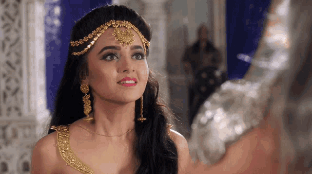 a woman is wearing a headpiece and earrings and smiling