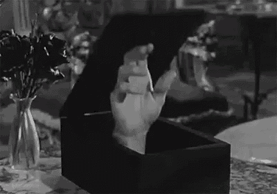 a black and white photo of a hand sticking out of a coffin .